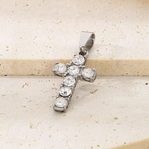 Macro shot of silver titanium cross pendant with clear crystals on stone background