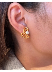 Macro view of gold filigree butterfly earring with pearl and zircon on model ear