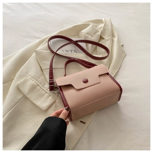 Detail of pink and burgundy lychee pattern PU leather crossbody bag on beige suit jacket