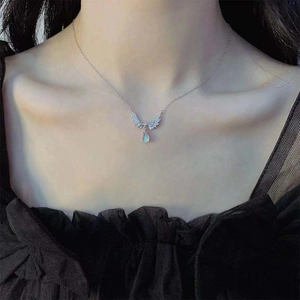 Detailed view of angel wing necklace with blue teardrop stone on model neck