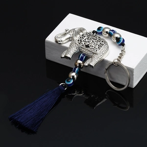 Detail of silver elephant keychain with blue evil eye beads and decorative fringe