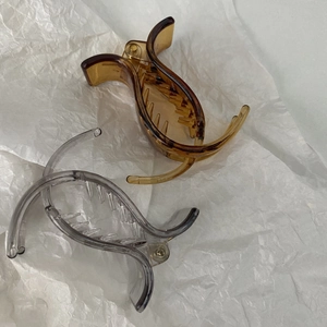 Detail view of small amber and grey claw clips for high ponytail styling on white paper