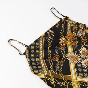 Détail du tissu satiné imprimé chaînes dorées sur mini robe noire à bretelles
