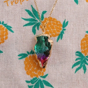 Close-up of a gold-edged triangular crystal pendant necklace in green and purple gradient