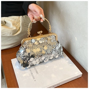 Macro detail of silver sequin evening bag with gold metal frame and spherical clasp