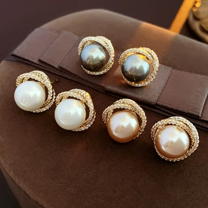 Detail of three pearl earrings with zircon halo in white, grey and champagne gold