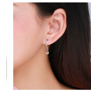 Close-up of a model wearing silver safety pin earrings with micro-pave zircon crystals