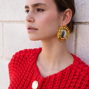 Detail of vintage gold and silver tone oval earrings worn with a red knit sweater