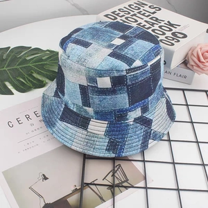 Detail view of denim patchwork bucket hat with white stitching on marble surface