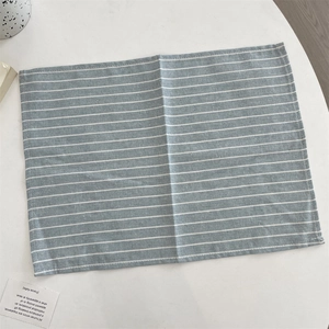 Gros plan sur un set de table rayé bleu clair en coton et lin avec bord cousu
