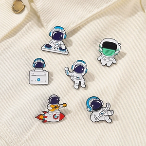 Detailed view of six astronaut enamel pins featuring creative poses on corduroy fabric