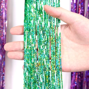 Close-up of sparkling green laser foil fringe curtain texture held by hand