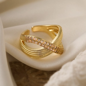 Elegant 18K gold plated criss-cross open ring with zircon stones on silk background