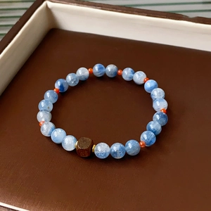 Detail view of square sandalwood bead and blue crystal gemstone on a classic bracelet