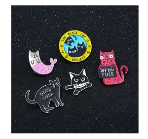 Close-up of assorted enamel cat pins with diverse funny designs on a black background