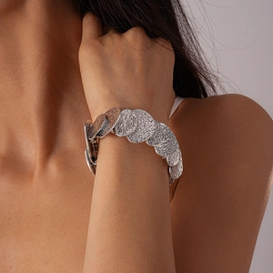 Detail of layered wavy silver and bronze metal bracelet on model's wrist