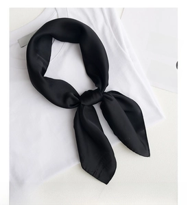Close-up of a elegant black silk scarf tied in a knot on a white cotton T-shirt backdrop