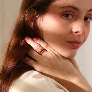Detail of 18K gold-plated layered rings with knot design and crystals on a hand