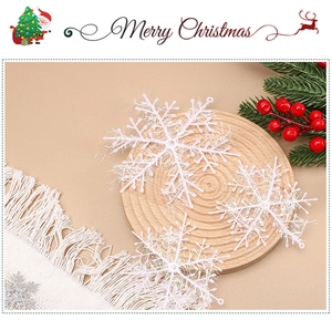 Close-up of three white glitter snowflake ornaments on a wooden tray with pine needles