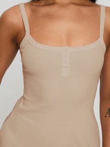 Détail de la robe côtelée beige avec de fines bretelles et trois boutons sur la poitrine