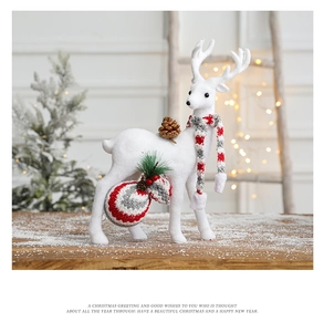 Close-up of a white flocked reindeer ornament with a striped scarf and pine cone detail