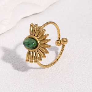 Detailed shot of 18k gold plated ring with emerald green stone and sun petal design