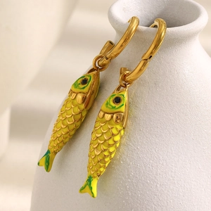 Macro detail of gold-plated fish earrings with yellow enamel and green scales texture