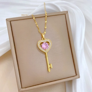 Close-up of heart key necklace with pink gemstone and crystals on beige jewelry box