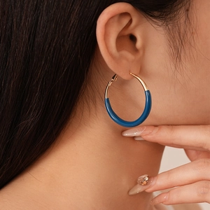 Minimalist gold hoop earrings with dark blue enamel geometric design on female model