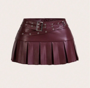 Détail d'une mini-jupe plissée en cuir PU bordeaux avec ceinture à boucle punk