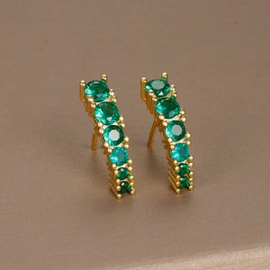 Elegant gold curved earrings with round green gemstones in a minimalist geometric style