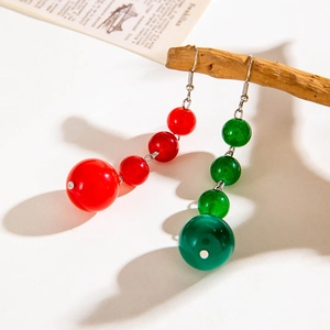 Detailed view of red and green beaded Christmas earrings hanging on a rustic branch