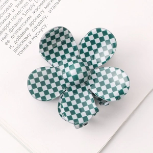 Top view of a green and white checkered flower claw clip on an open book page