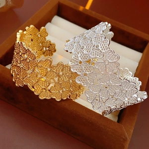 Detailed close-up of hollow clover flower bangle bracelets in gold and silver finish
