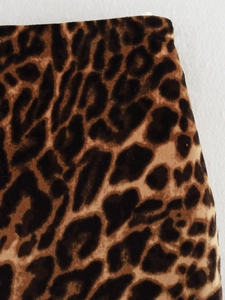 Close-up of suede leopard print fabric texture featuring brown and black patterns