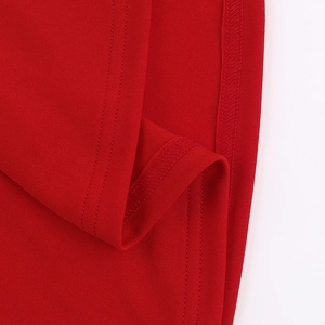 Détail macro de la robe courte rouge montrant le tissu tissé et l'ourlet à double couture