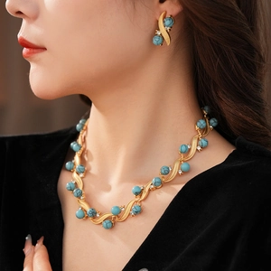 Detail of vintage turquoise jewelry set featuring gold necklace and earrings on model