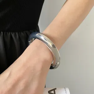 Gros plan d'un bracelet jonc argenté poli avec fermoir à charnière sur le poignet