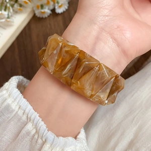 Close-up of amber acrylic geometric bracelet with marble texture and pyramid facets