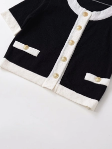 Close-up of contrast tweed cardigan featuring ornate gold embossed buttons and pocket details