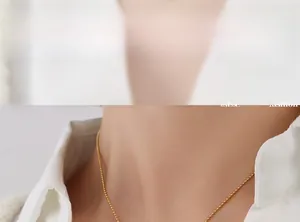 Close-up of minimalist golden bead chain necklace worn by a model with a white shirt