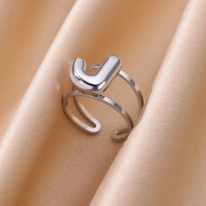 Detailed close-up of a silver alphabet J ring on champagne silk, showcasing adjustable design