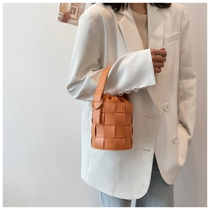 Fashionable orange woven bucket bag styled with a white blazer for a chic summer look