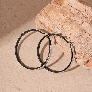 Detail of silver textured geometric hoop earrings with black matte inner ring