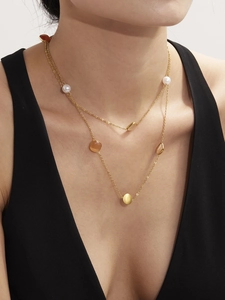 Detail einer mehrlagigen Goldkette mit Katzenaugensteinen und Perlen am Modelhals