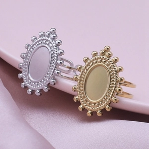 Close-up of gold and silver oval ring bases on pink porcelain with silk fabric texture
