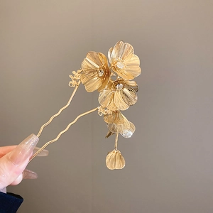 Detail of a golden flower hair pin with sparkling crystal rhinestones and a petal tassel