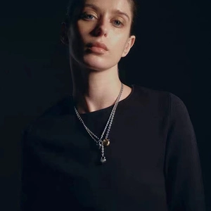 Close-up of double-layered gold and silver necklace with heart and lock charms on a model