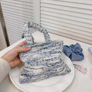 Dettaglio della mini borsa in tweed blu e bianca con etichetta simple e manico