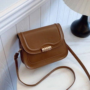 Sacoche en cuir marron avec boucle dorée sur marbre, sac à bandoulière vintage chic